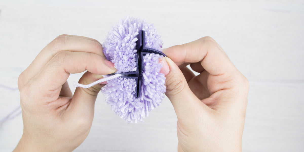 Die Schablonen eines Pompon Makers werden von einem fertigen Pompon entfernt.